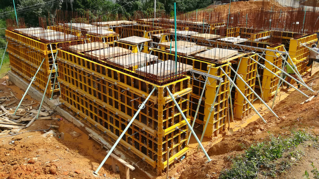 Sistema de encofrado modular vertical amarillo con puntales apuntalando muros en obra.